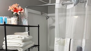 Ein Badezimmer mit Toilette, einer Dusche mit Blumendusche und einem Handtuchhalter mit gefalteten Handtüchern.
