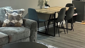 Ein modernes Wohnzimmer mit einer Couch, einem runden Couchtisch und einem Essbereich mit Stühlen und einem Tisch.