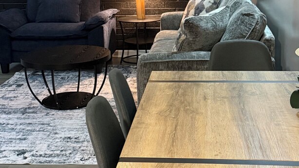 Ein gemütliches Zimmer mit Backsteinwand, einem runden Tisch und zwei Sofas.