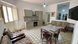 Um espaço de estar compacto com cozinha americana, área de jantar com mesa e cadeiras, e um sofá.