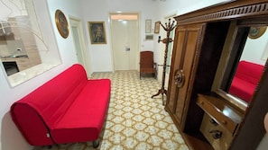 A room with a red sofa, a wooden cabinet, and a patterned floor.