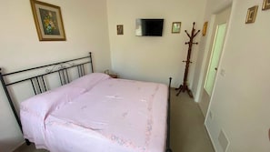 A bedroom with a bed, a television mounted on the wall, and a coat stand. - Casa Vacanze Dimora dei Campioni (Taranto)