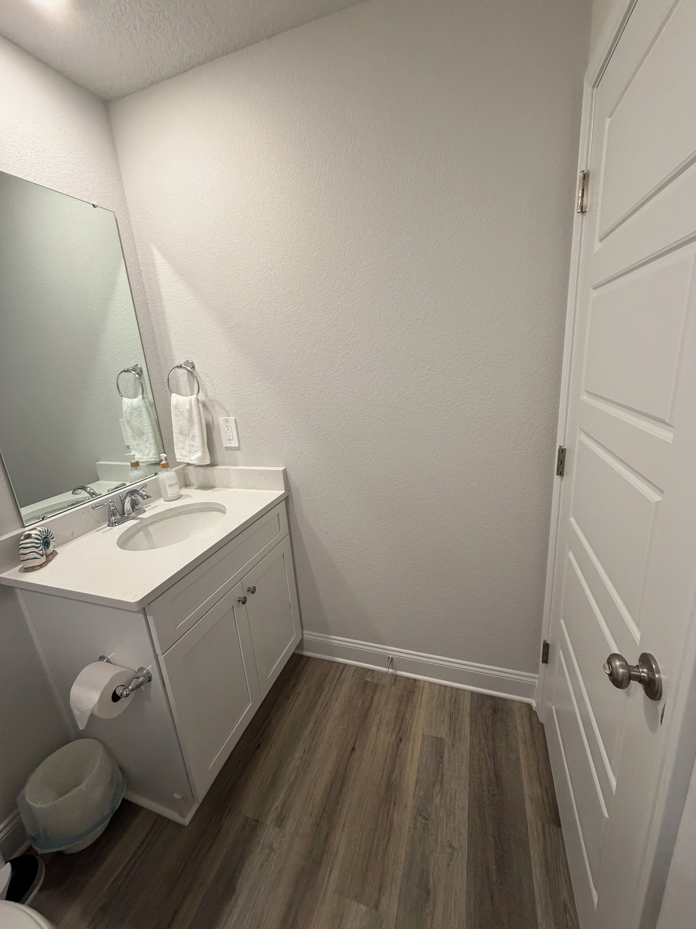 A bathroom with a white sink, mirror, and white cabinets.
