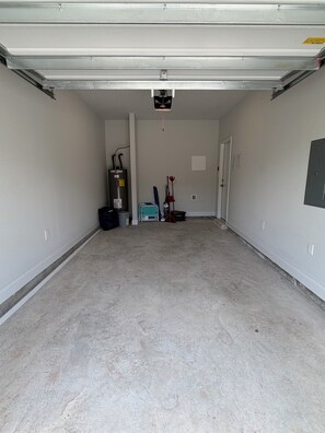 Eine geräumige Garage mit Betonboden, geschlossenem Garagentor und einer Deckenleuchte.