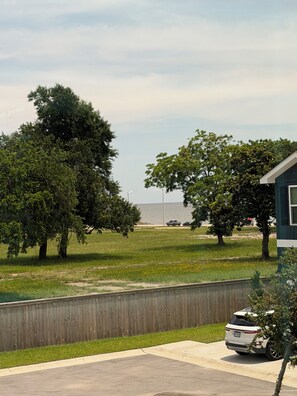 Ein Wohngebiet mit einem Haus, einem eingezäunten Garten, einem geparkten Auto und Blick aufs Meer.