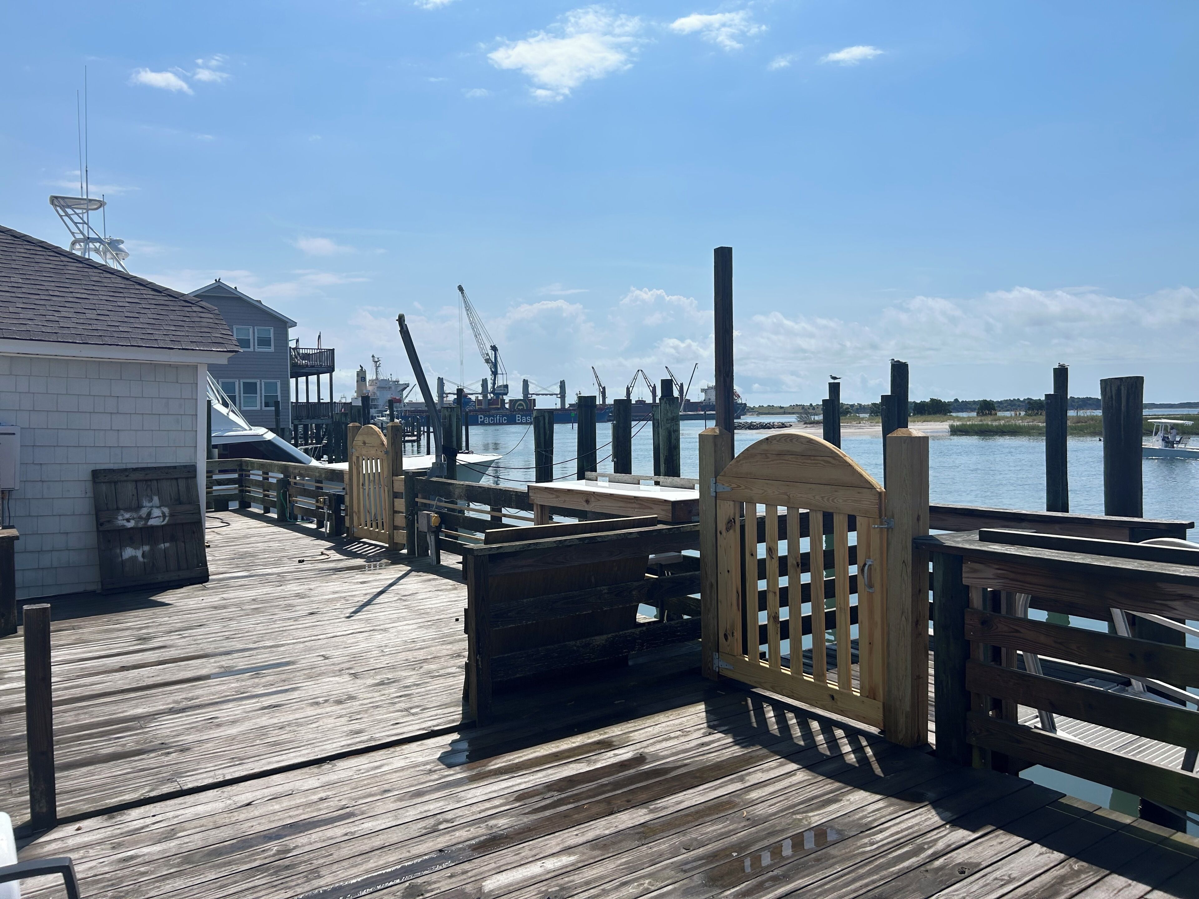 A wooden pier with a gate, a dock, and a building with a satellite dish.