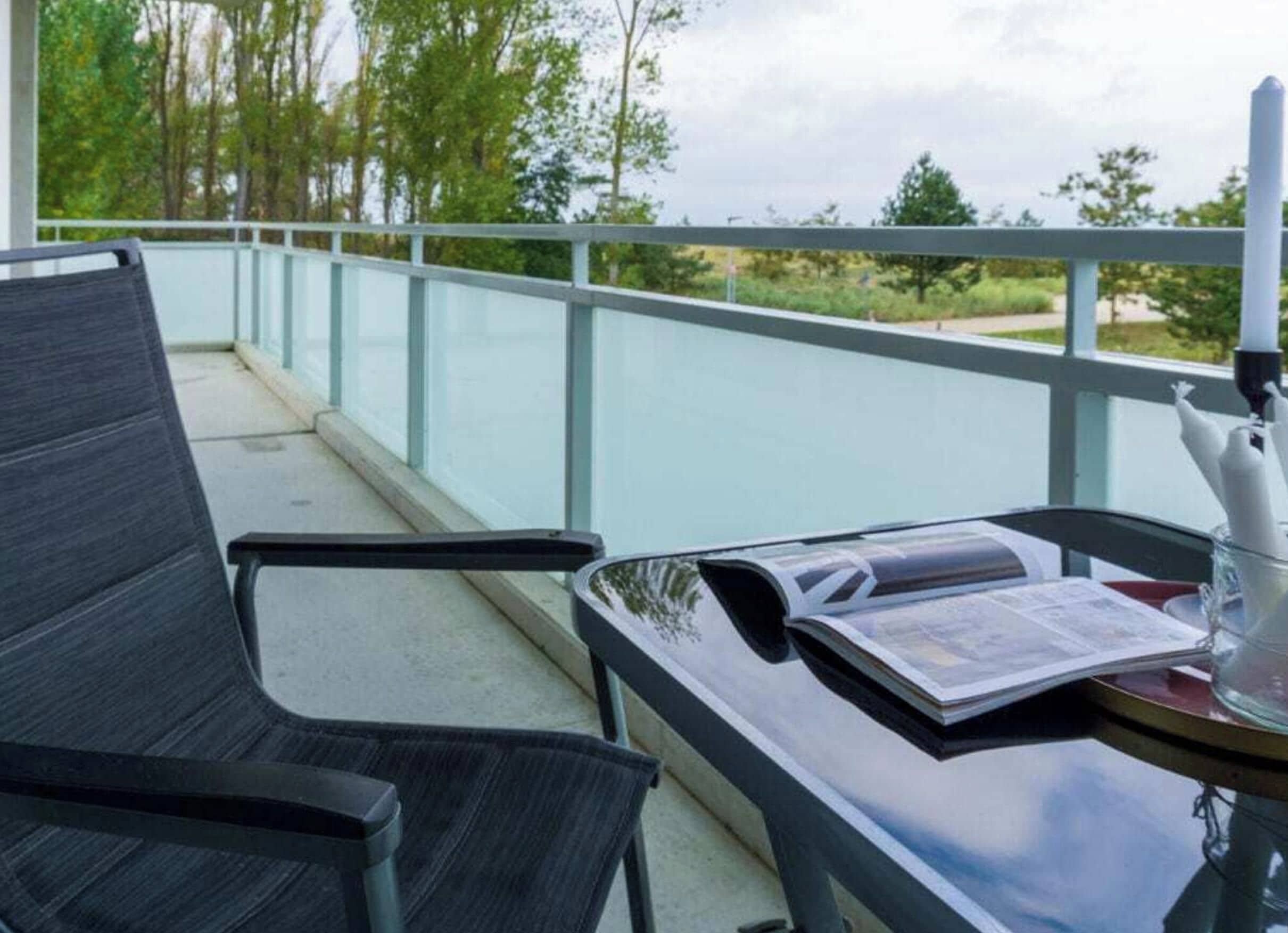 Een balkon met een stoel, een tafel en een boek.