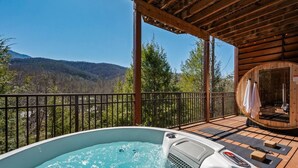 Ein Whirlpool auf einer Holzterrasse mit Blick auf einen Wald und Berge.