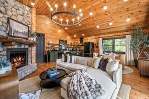 A cozy cabin interior with a stone fireplace, a wooden ceiling, a dining area, and a kitchen. - Radford Place~ A Couples Retreat (Gatlinburg)