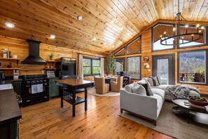 A spacious living area with a large sofa, a dining table, and a kitchen with a stove and refrigerator. - Radford Place~ A Couples Retreat (Gatlinburg)