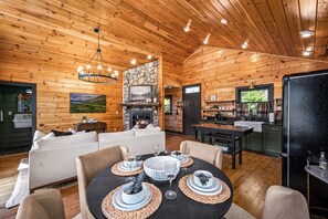 A cozy cabin interior with a dining area, living room, kitchen, and a fireplace. - Radford Place~ A Couples Retreat (Gatlinburg)