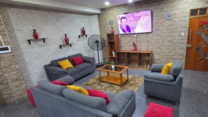 A living room with grey sofas, a coffee table, and a TV mounted on the wall. - Ximena's House: It offers the space and freedom your family needs. (Iquitos)