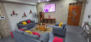 Una sala de estar con sofás grises, una mesa de centro y un televisor montado en la pared.