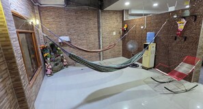 Una habitación con una hamaca, un ventilador y una silla roja.