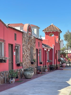 Filas de edificios con muros rojos y detalles de piedra, con balcones adornados con plantas en macetas.