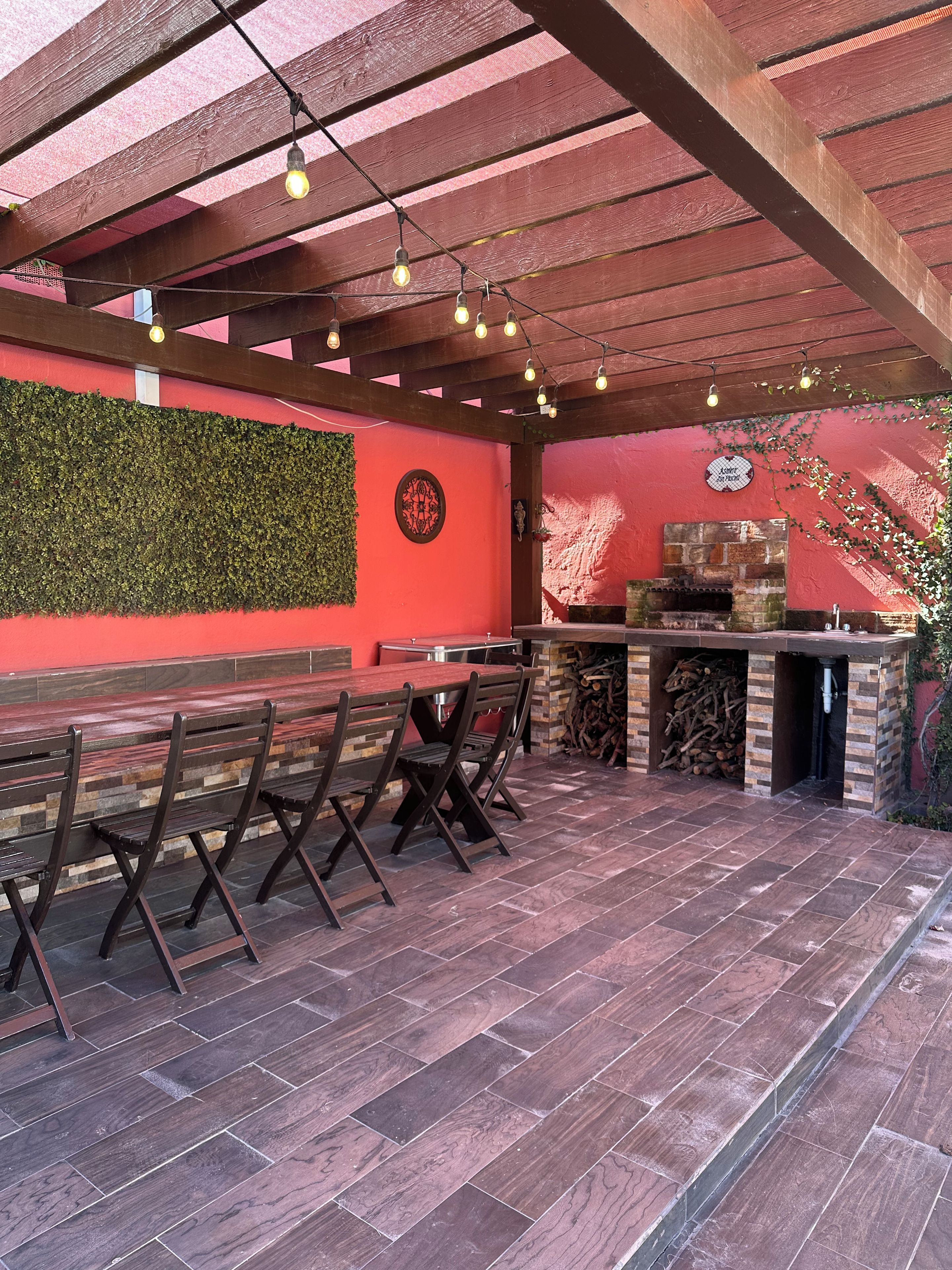 Un patio al aire libre con bancos de madera y una chimenea de ladrillo.