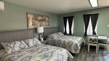 A bedroom with two beds, a desk, and a chair.