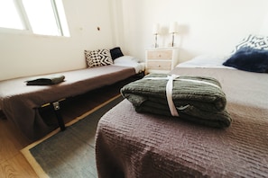 Une chambre avec deux lits, une table de chevet avec des bougies et une fenêtre.