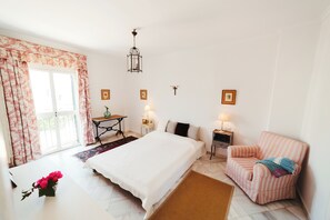 Une chambre à coucher avec un grand lit, une chaise, une table et un luminaire suspendu.