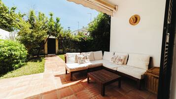 A patio with a white sofa, a wooden table, and a wicker basket.