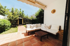 A patio with a white sofa, a wooden table, and a wicker basket.