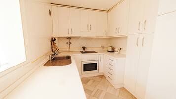 A kitchen with white cabinets, a stainless steel sink, a stove, and a toaster.