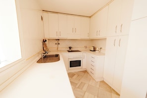 A kitchen with white cabinets, a stainless steel sink, a stove, and a toaster.