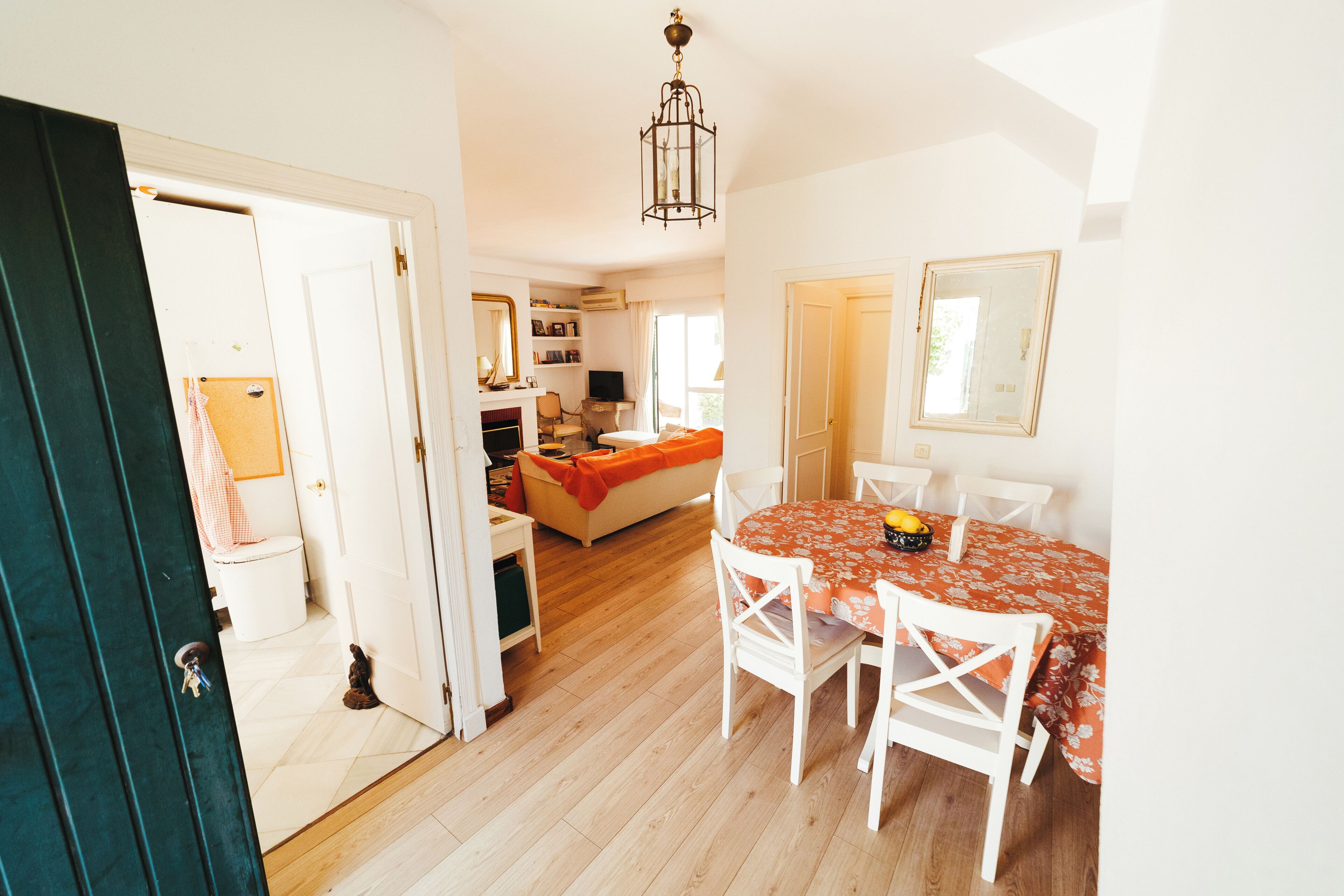 A room with a dining table, chairs, a sofa, a television, and a mirror.