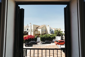 A residential street with parked cars and houses with tiled roofs.