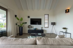 Una sala moderna con un sofá, una mesa de centro, un televisor y una planta en maceta.