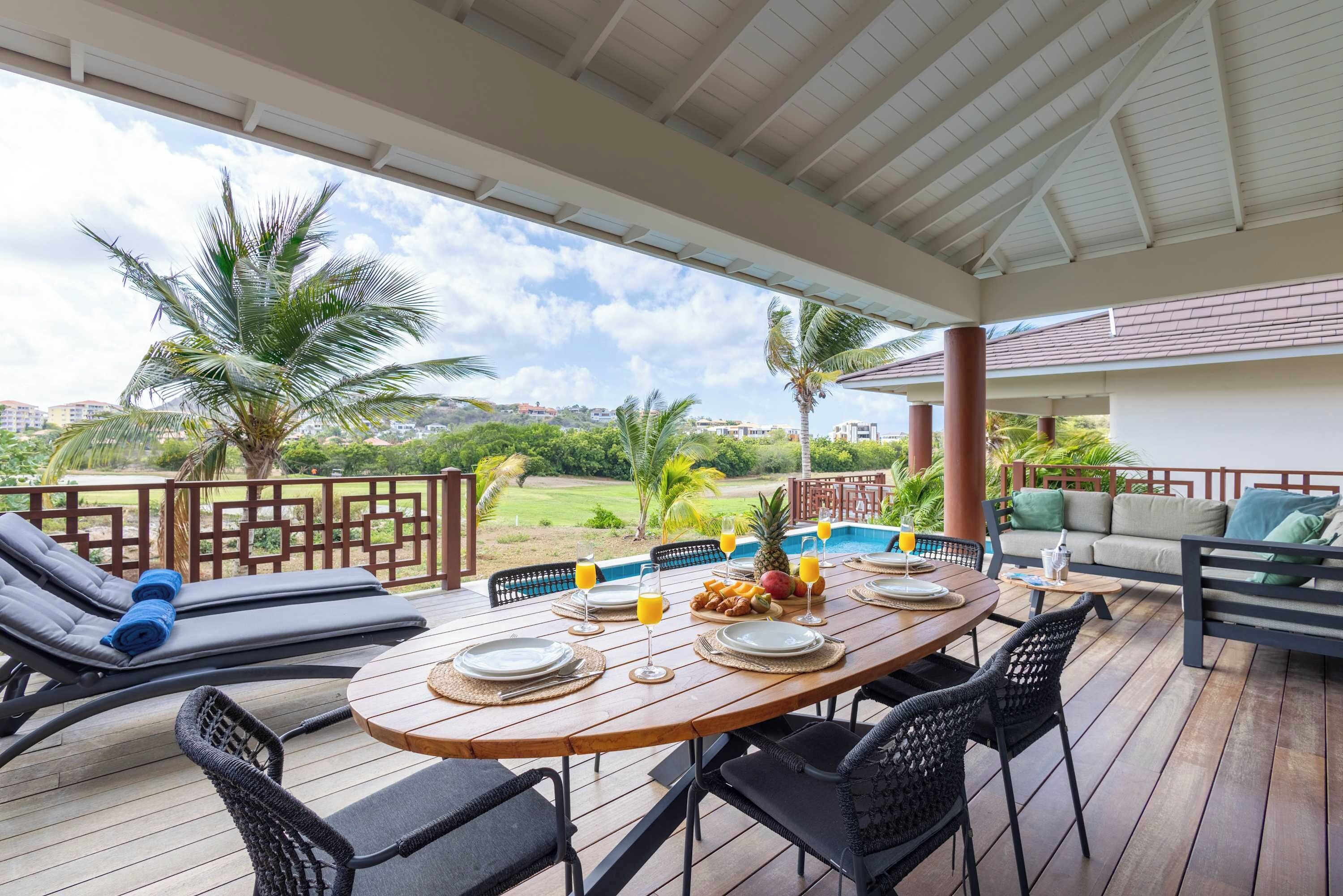 Un espacio de comedor al aire libre cubierto con piscina, sillones reclinables y vistas al paisaje.
