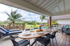 Un espacio de comedor al aire libre cubierto con piscina, sillones reclinables y vistas al paisaje.