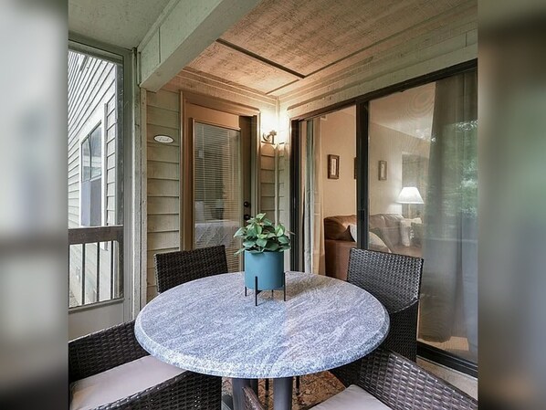 A round table with chairs and a potted plant in a covered outdoor area with a view of a house. - 2BR/2BA Taneycomo Lake Views +Resort Perks + Pet Friendly (Branson)
