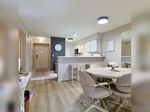 A modern kitchen with white cabinets, a central island, and a dining area with a table and chairs. - 2BR/2BA Taneycomo Lake Views +Resort Perks + Pet Friendly (Branson)