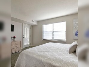 A bedroom with a bed, a dresser, a door, and a window. - 2BR/2BA Taneycomo Lake Views +Resort Perks + Pet Friendly (Branson)