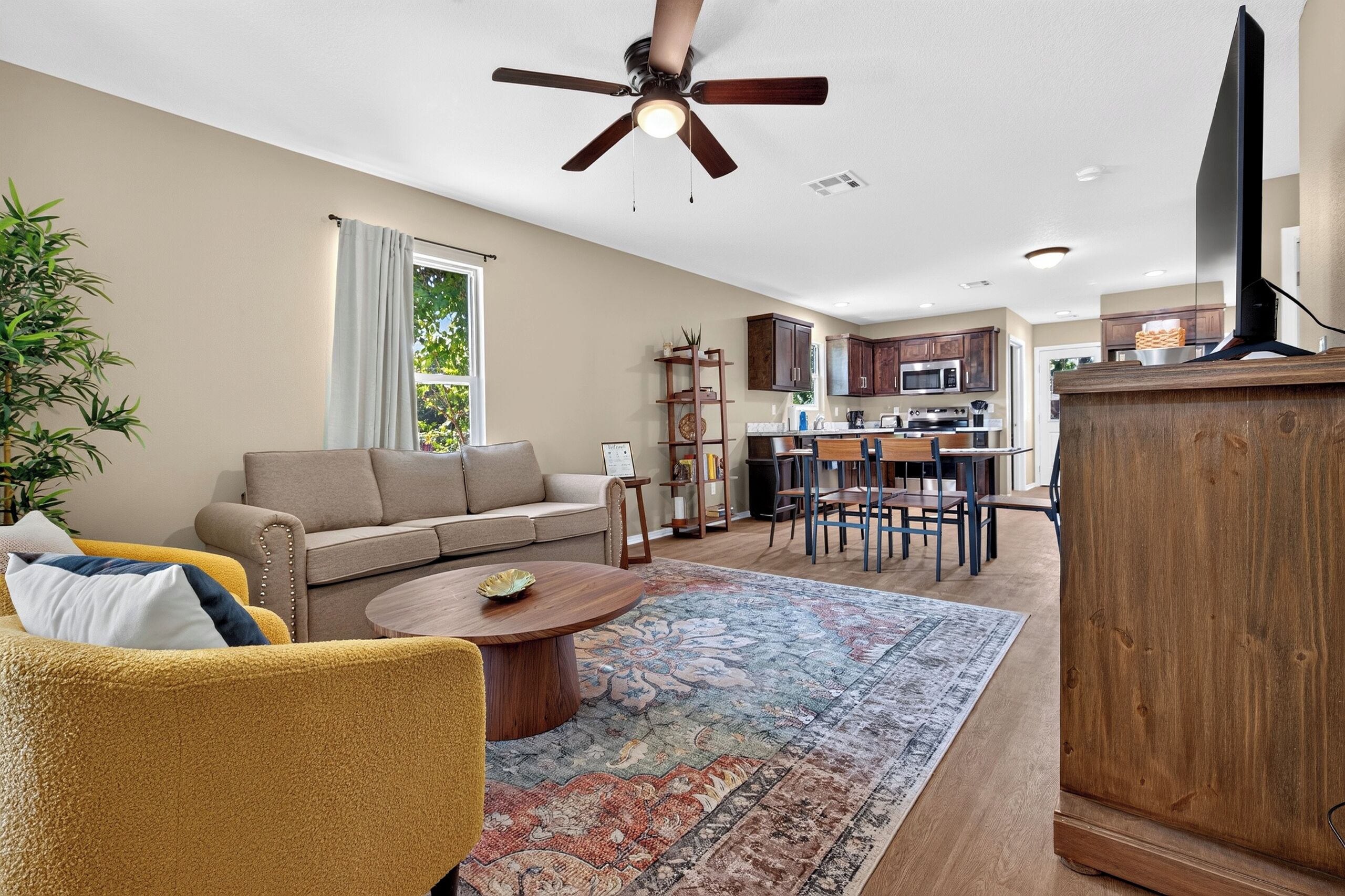 A modern living room with a sofa, coffee table, and a dining area with chairs and a table.