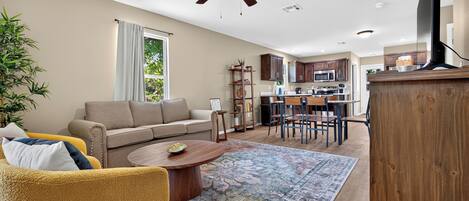A modern living room with a sofa, coffee table, and a dining area with chairs and a table.
