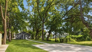 A residential area with a single-story house, a well-maintained lawn, and a clear sky.