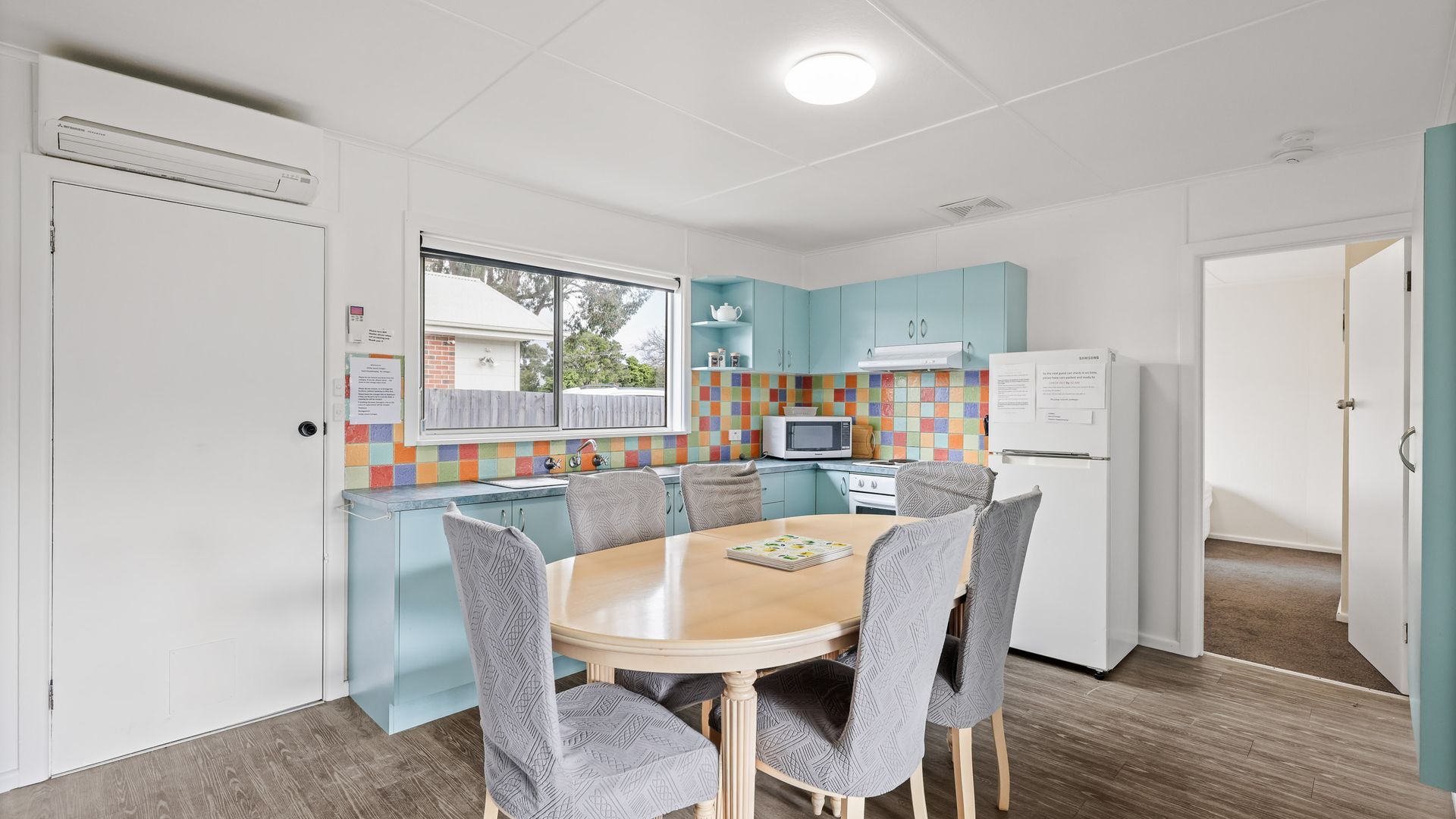 Una cocina compacta con una mesa de comedor, sillas, microondas, estufa y refrigerador.