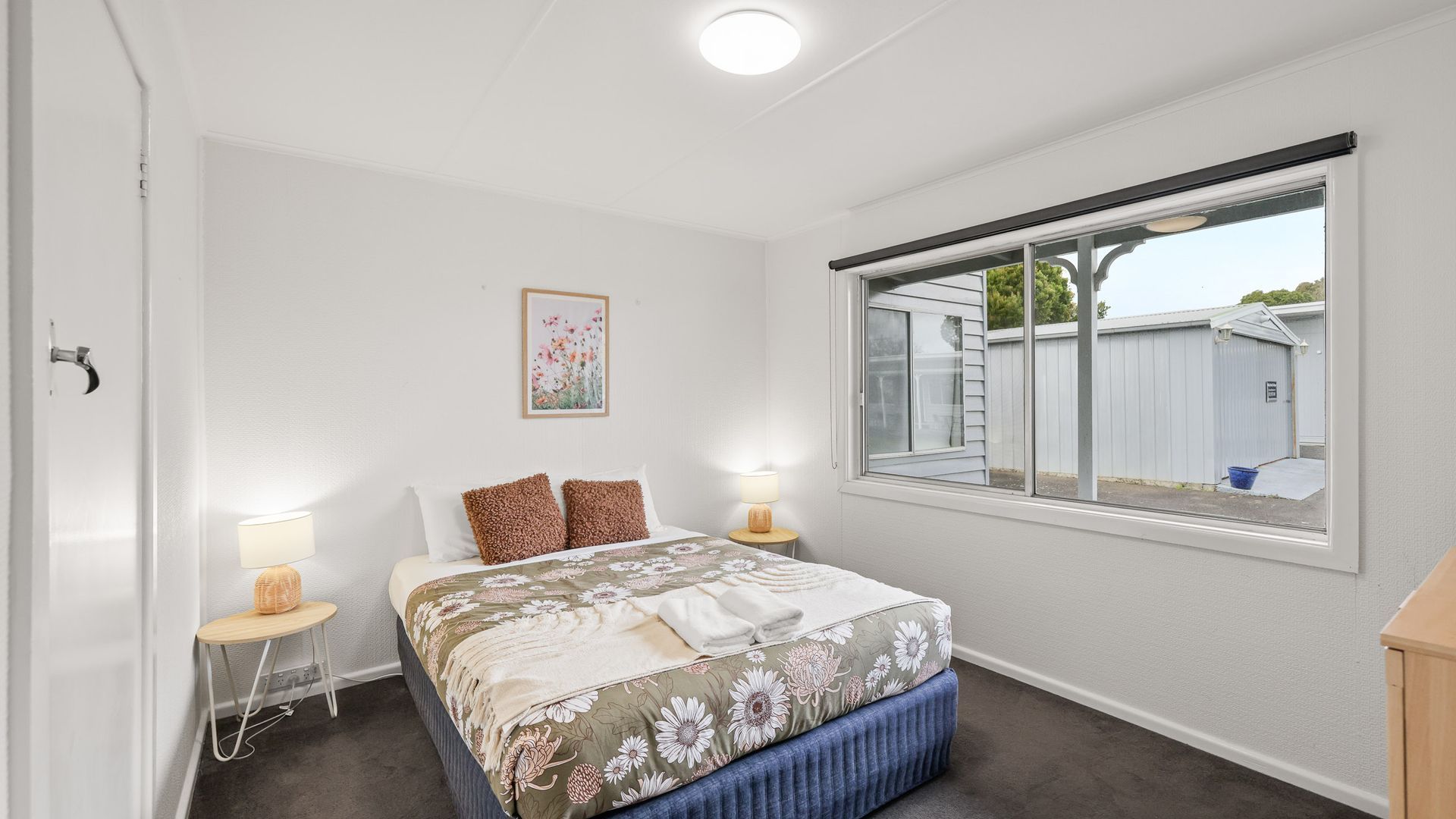 A bedroom with a bed, two bedside tables, a window, and a door.