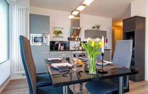 Eine moderne Küche mit Esstisch, Stühlen und einer Blumenvase.