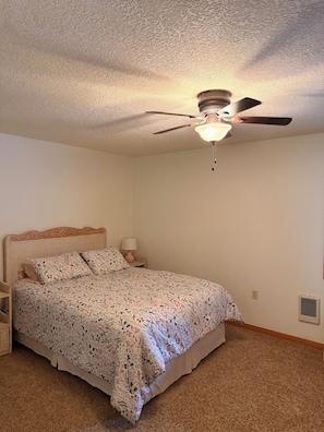 A bedroom with a bed, a nightstand, a lamp, a ceiling fan, and a wall vent. - Cozy 2 bedroom condo in amazing Mount Hood Village with AC on the golf course. (Mount Hood Village)