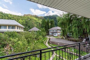A residential area with a paved driveway, a balcony with a wrought iron railing, and houses with sloped roofs.