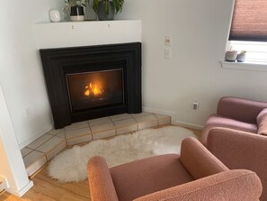 A living room with a fireplace, a white rug, and two pink sofas.