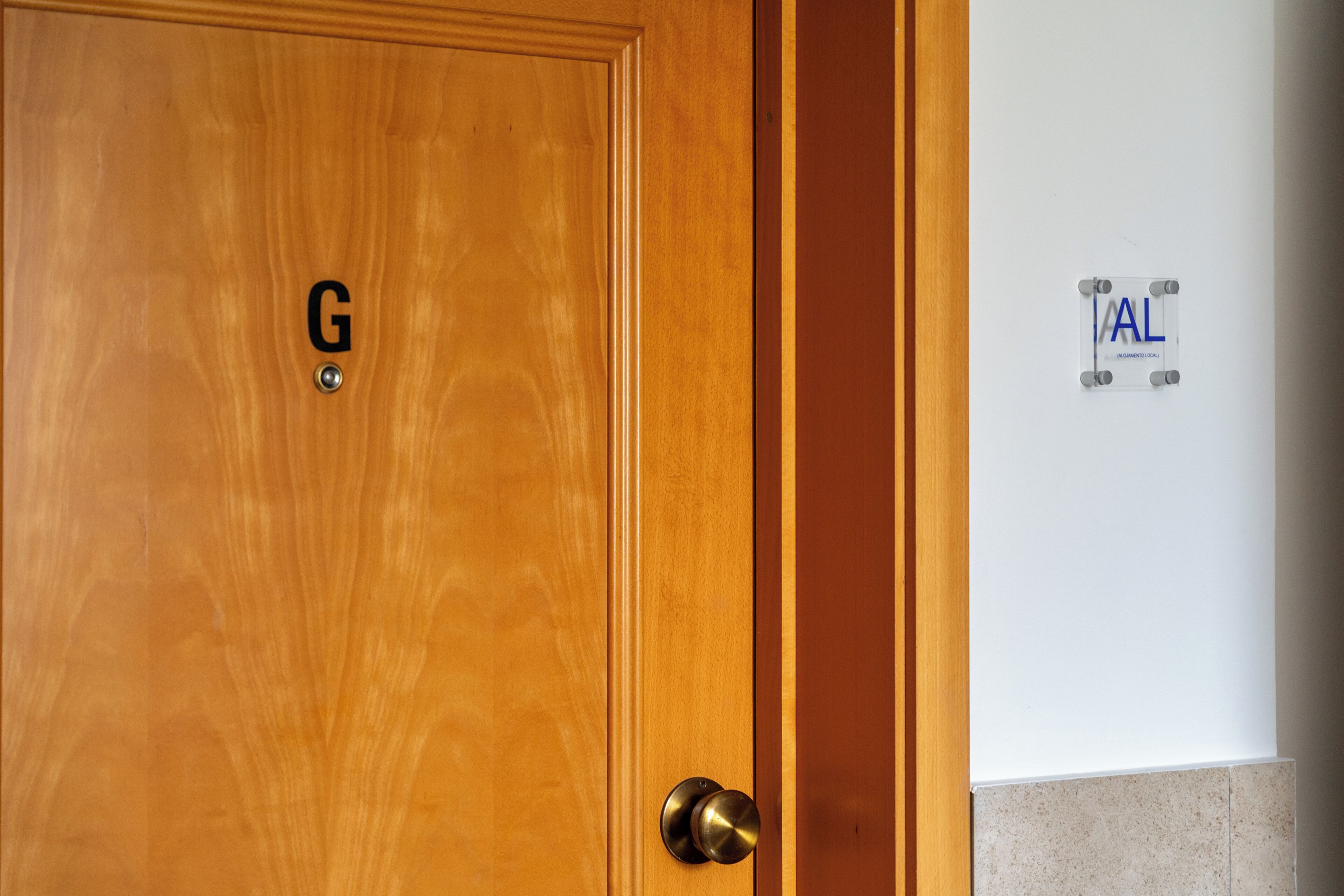 Una porta di legno con una maniglia in ottone e una targhetta con la lettera 'G'.