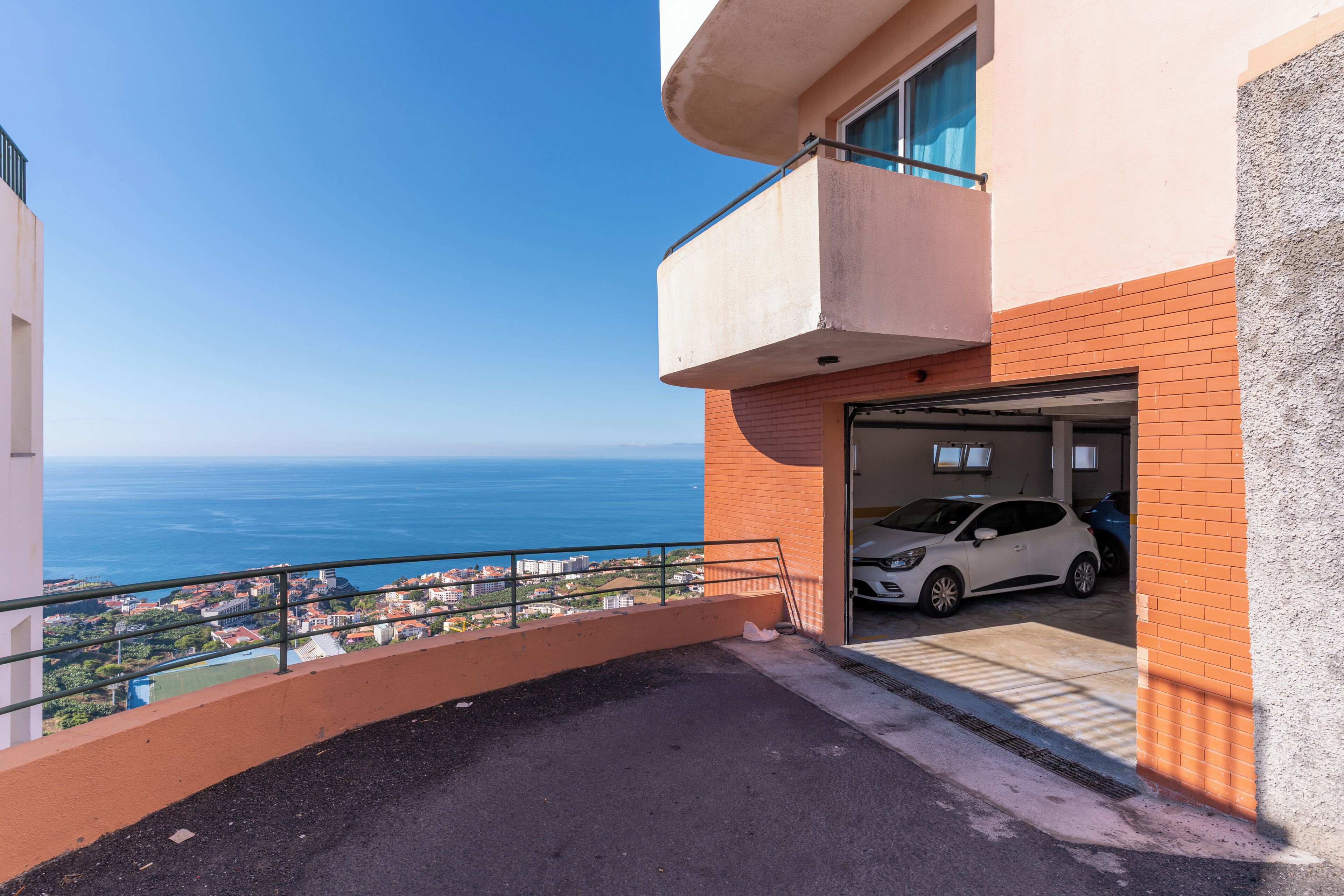 A residential building with a garage, a balcony, and a view of the sea.