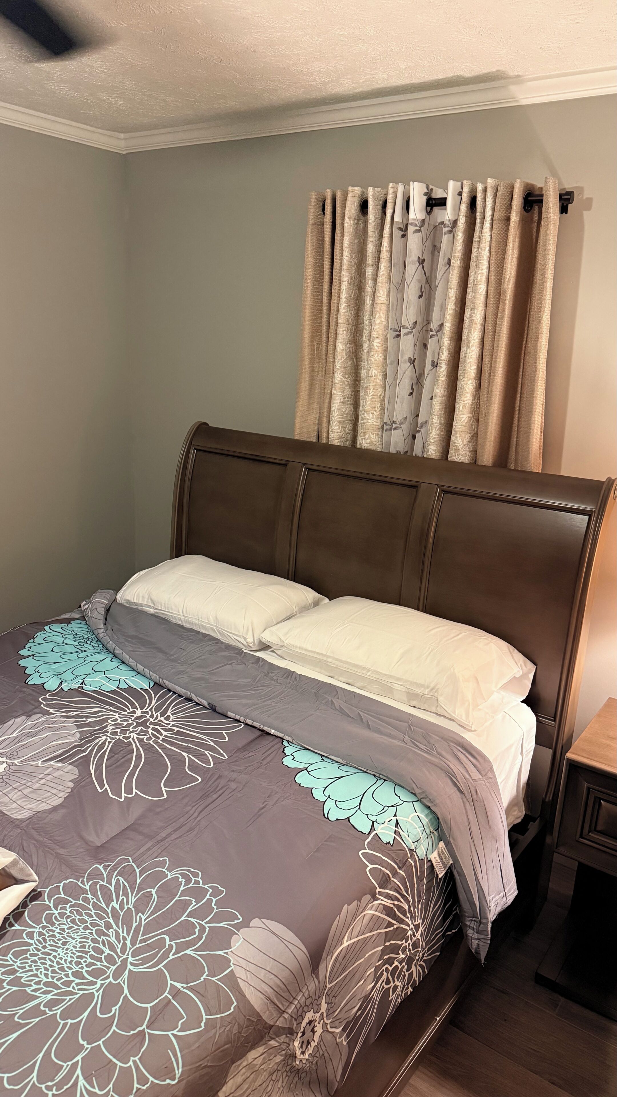 A bedroom with a bed, curtains, and a nightstand.