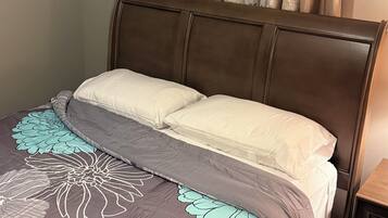 A bedroom with a bed, curtains, and a nightstand.