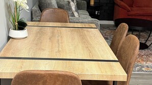 A modern dining area with a wooden table, two chairs, a sofa, and a red chair. - The Cove #4. Rare find. Comfy 2Bedroom apartment in soothing Rockingham with AC. (Rockingham)