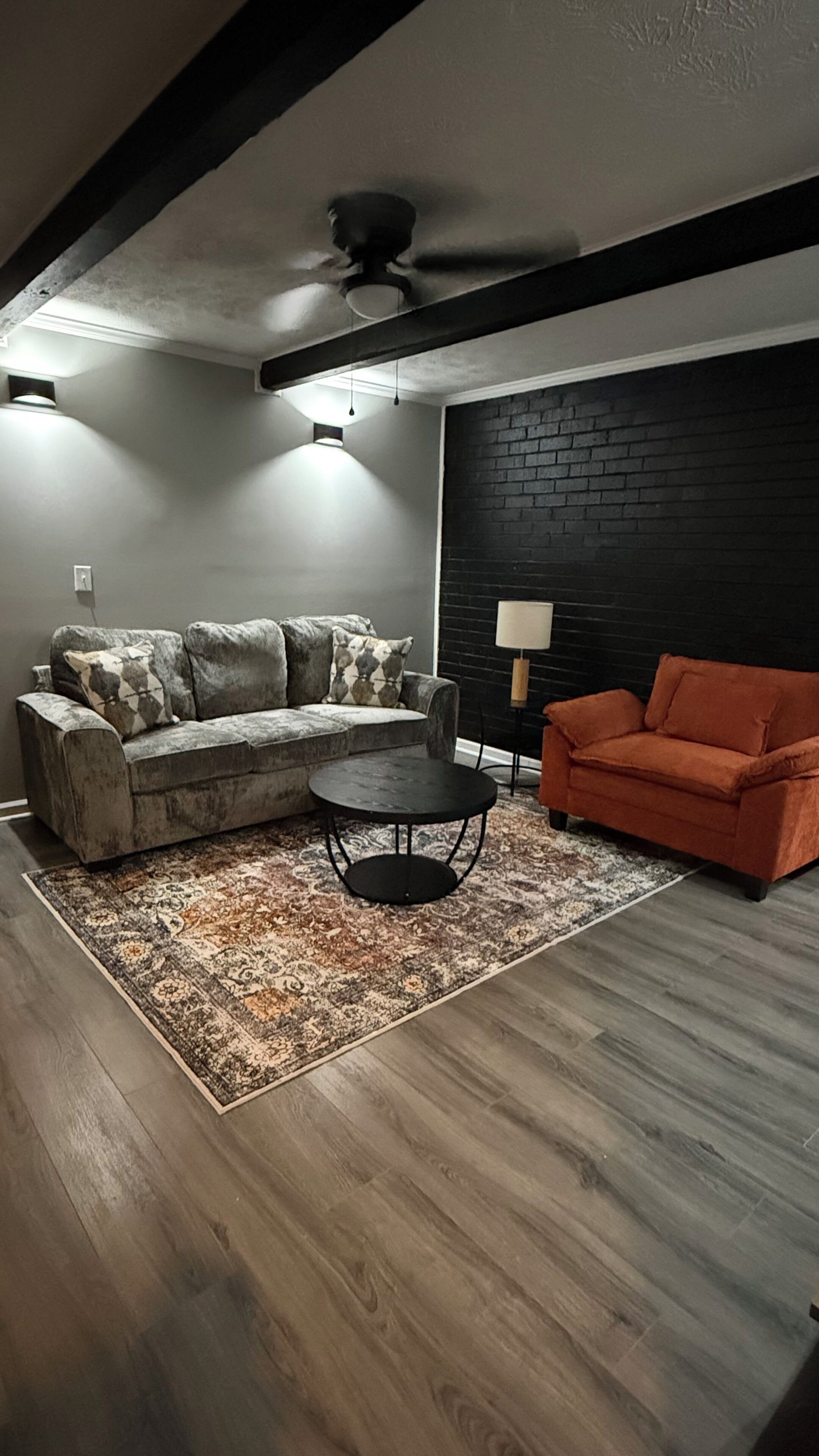 A living room with a sofa, a coffee table, and a red armchair.